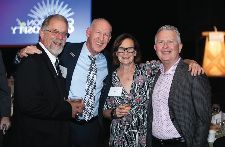 Four people smile together at event.