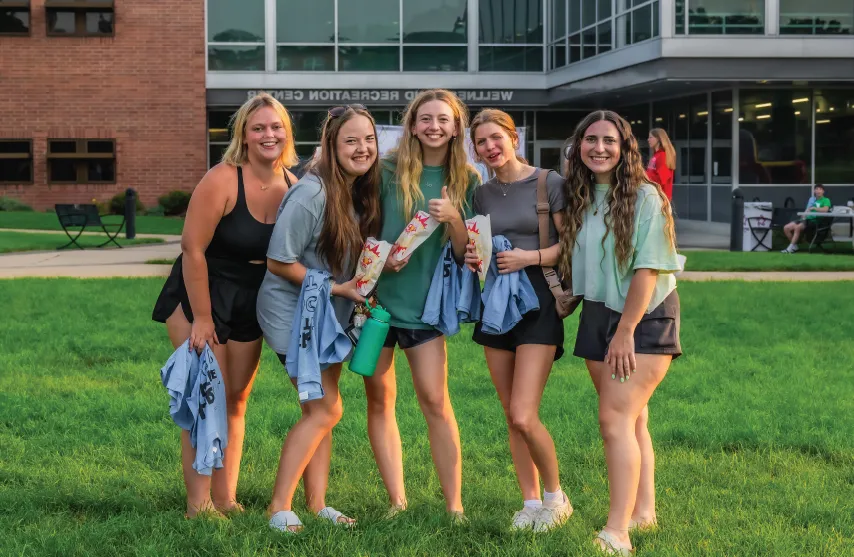 A group of students smiling outdoors in front of the 康体娱乐中心.